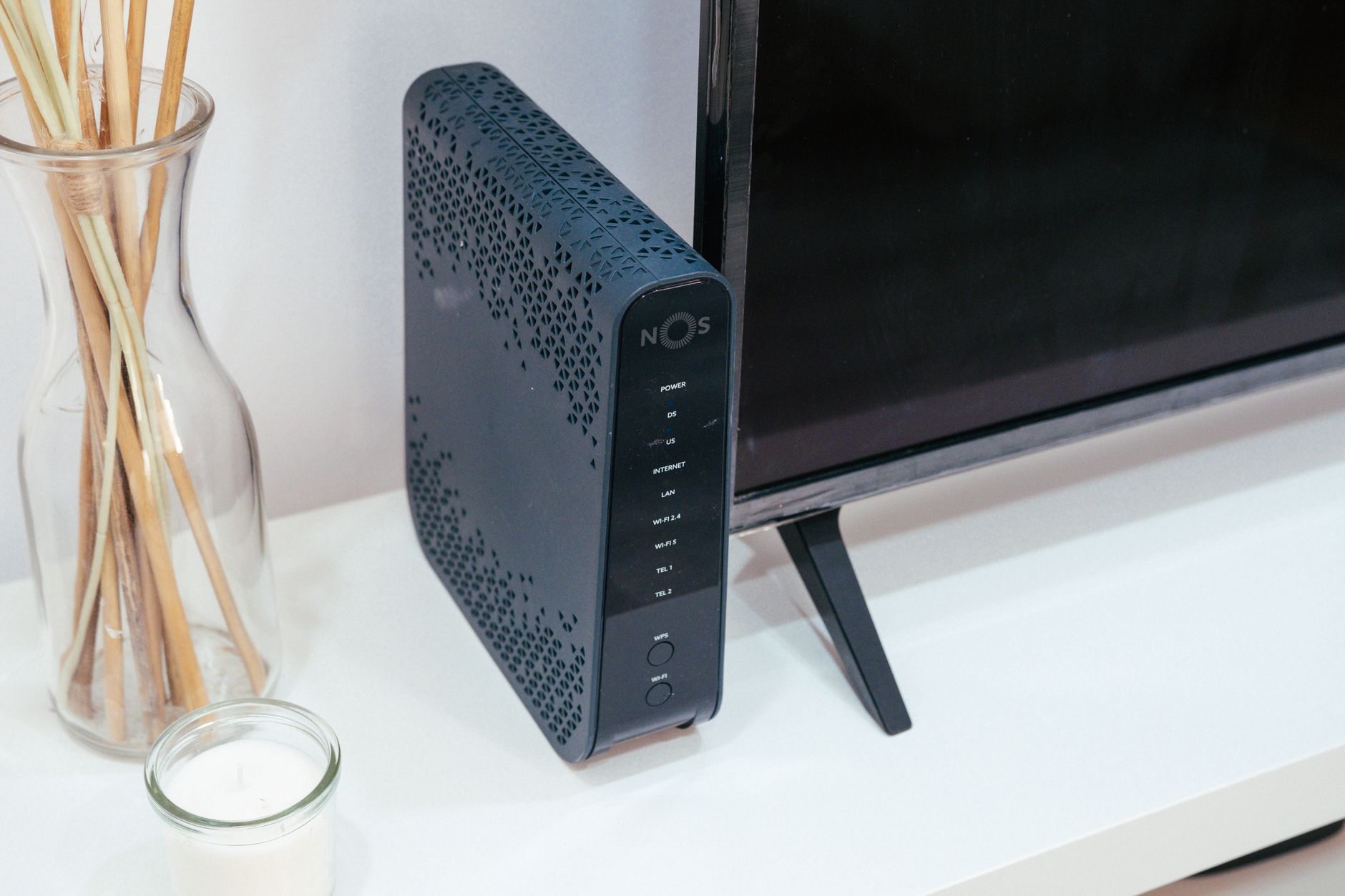 A wireless router on a shelf in a home office with cables visible