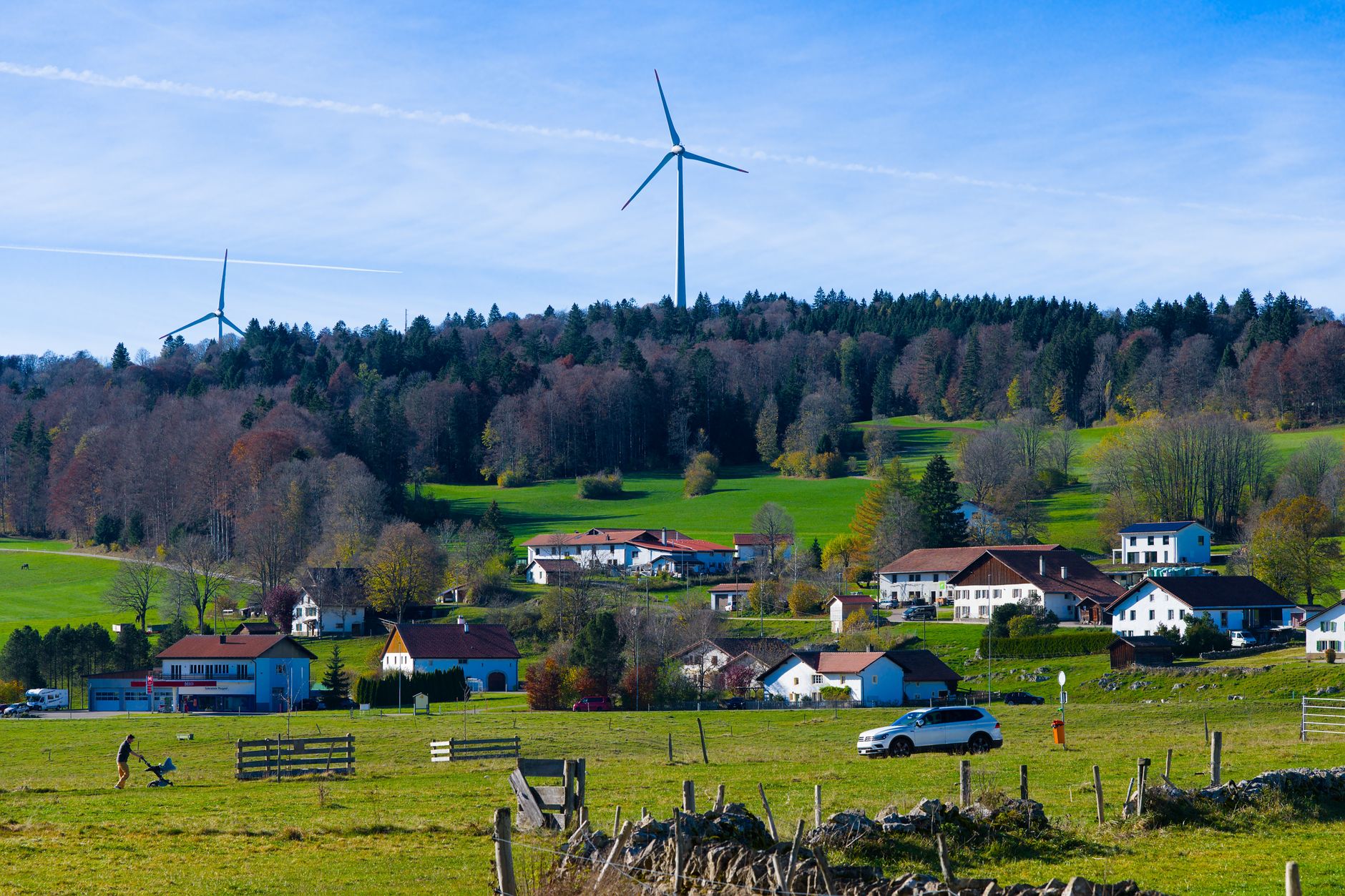 A wind turbine on a green hillside beside a small building