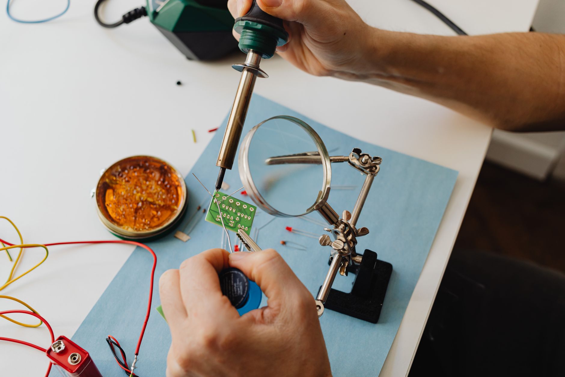 A technician repairing a laptop at a workbench with tools and parts