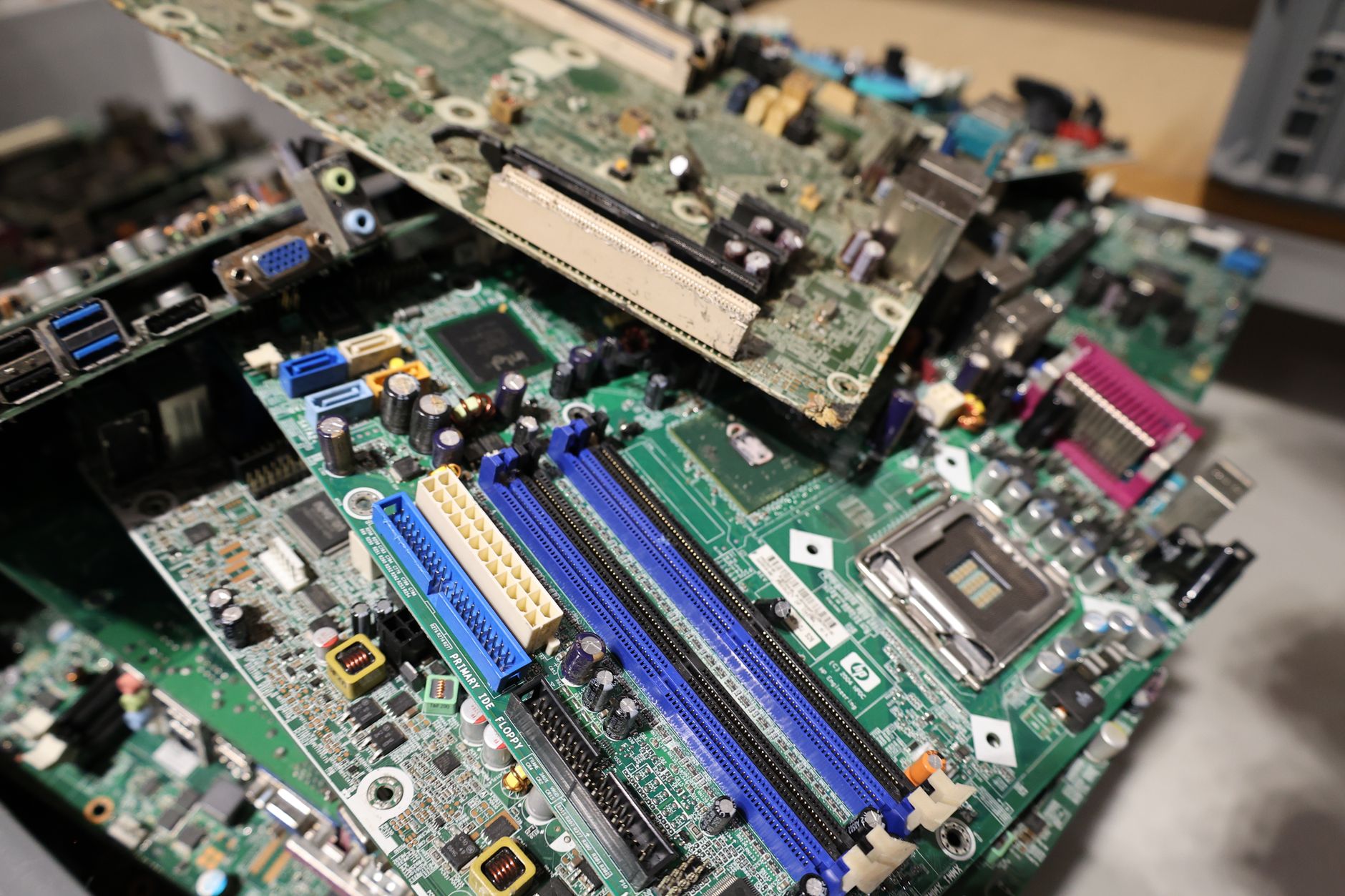 Stacked old laptops and computer parts at an electronics recycling facility